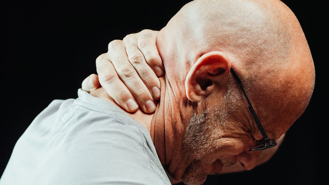 Side view of senior man holding neck with visible discomfort, highlighting neck pain relief.